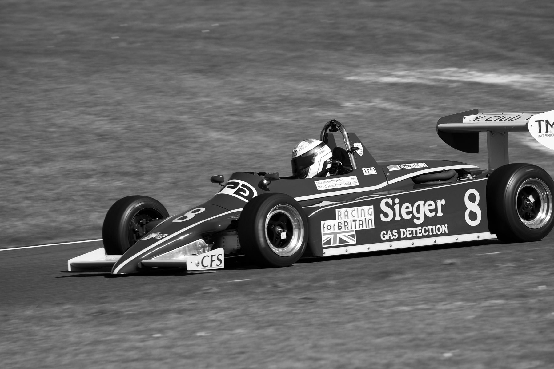 A dark Formula 3 car with the number 8 and ‘Sieger Gas Detection’ in pale letters on its sidepod, seen side-on on a circuit bordered by grass.