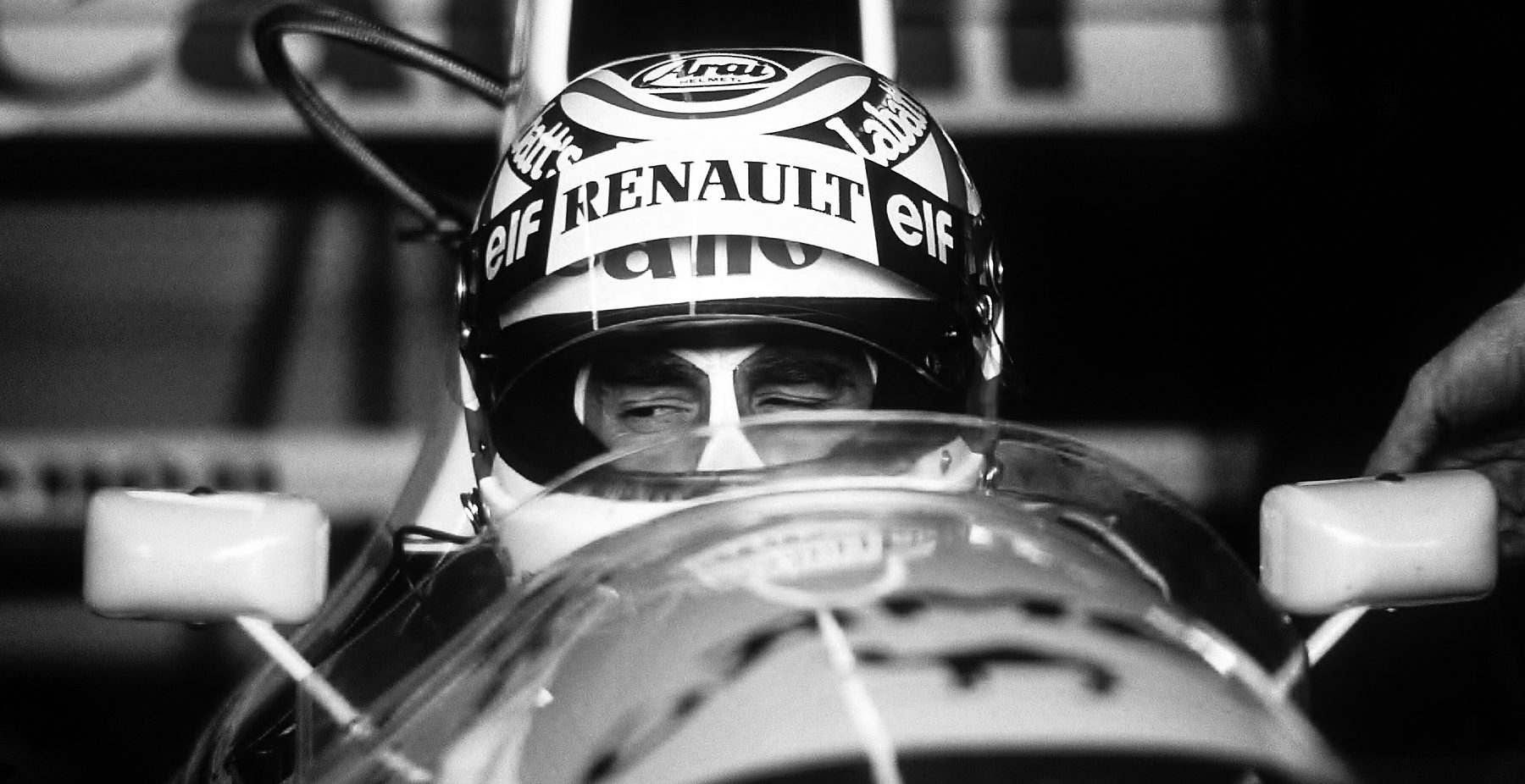 Head-on, a driver in a banded helmet lettered ‘Renault’ and ‘elf’ sits low in the cockpit, only his eyes visible, a mirror on either side.