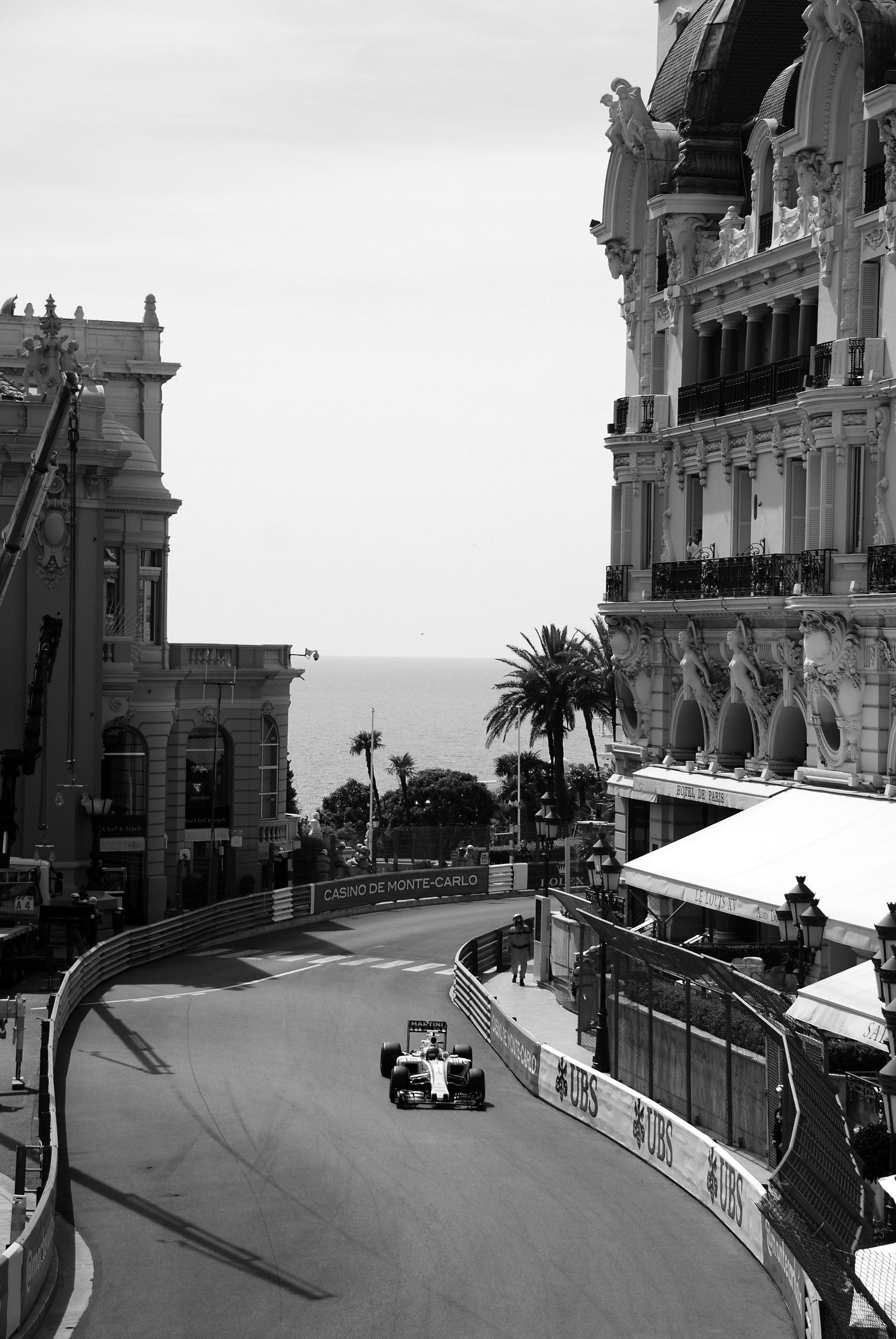A narrow street circuit climbs between the ornate façades of grand hotels towards a glimpse of the sea, a single racing car rounding the bend between the barriers.
